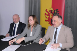 Trzy osoby podpisują umowę. Dokonują tego kobieta i dwóch mężczyzn 
