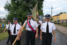 Strażacy. Jeden z nich niesie sztandar 