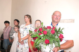 Grupa osób, mężczyzna trzyma kwiaty