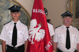 Strażacy. Jeden z nich trzyma sztandar 