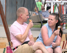 Kobieta i mężczyzna siedzą na ławce i jedzą lody