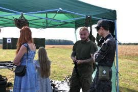 Grupa osób przy stoisku militarnym 