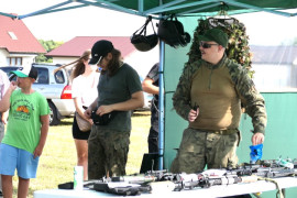 Grupa osób przy stoisku militarnym 