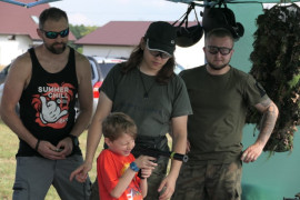 Mężczyźni i chłopiec przy stoisku militarnym 