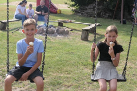 Dziewczynka i chłopiec siedzący na huśtawce. Dzieci jedzą lody 