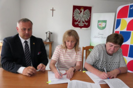 Dwie kobiety i mężczyzna siedzą przy stole. Moment podpisywania umowy