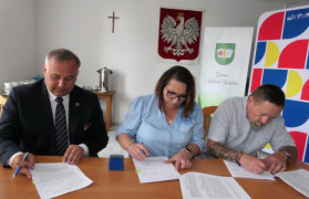 Kobieta i dwaj mężczyźni podczas podpisywania umowy