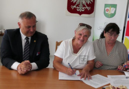 Dwie kobiety i mężczyzna siedzą przy stole. Moment podpisywania umowy