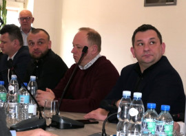 Mężczyźni siedzą przy stole. Trwają obrady rady gminy
