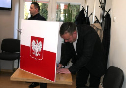 Dwaj mężczyźni. Jeden z nich znajduje się przy stole do głosowania 