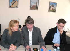 Kobieta i dwaj mężczyźni siedzą obok siebie. Trwają obrady rady gminy