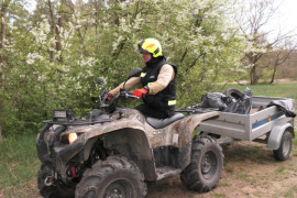 Mężczyzna jedzie na quadzie. Quad ciągnie przyczepkę, na której znajdują się odpady zebrane podczas sprzątania rzeki Warty 