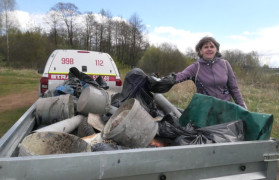 Kobieta wrzuca worek z odpadami, zebranymi podczas sprzątania rzeki Warty