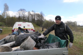 Mężczyzna wkłada worek z odpadami na przyczepkę 