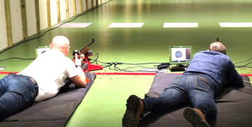 Dwaj mężczyźni strzelają z broni na strzelnicy sportowej 
