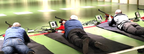 Trzej mężczyźni strzelają z broni na strzelnicy sportowej 