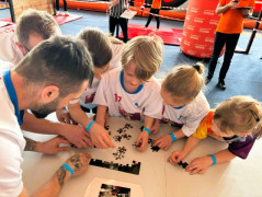 Dzieci i dorośli układają puzzle. Uczestnicy sportowego turnieju