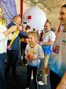 Moment wręczania dziewczynce medalu za udział w turnieju sportowym 