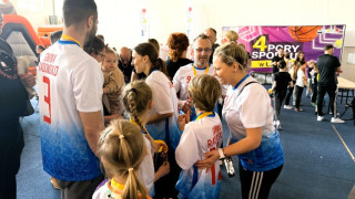 Grupa osób w kolorowych koszulkach stoi obok siebie. Osoby tworzą koło
