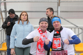 Dwaj mężczyźni stoją obok siebie. Obaj mają szaliki z godłem Polski