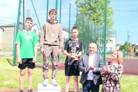 Kobieta, mężczyzna i młodzi zawodnicy stojący na podium 