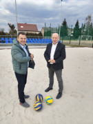 Dwaj mężczyźni stoją obok siebie. Mężczyźni znajdują się na boisku do gry w piłkę siatkową 