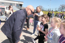 Mężczyzna wręcza medale uczestniczkom biegu 