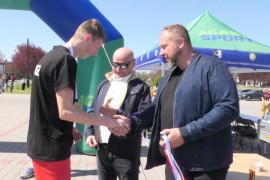 Dwaj mężczyźni wręczają medal uczestnikowi biegu 