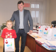 Dziewczynka i mężczyzna. Dziewczynka trzyma w ręku upominkową torbę 