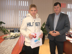 Chłopiec i mężczyzna stoją obok siebie. Chłopiec trzyma w ręku upominkową torbę 