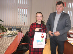 Dziewczynka i mężczyzna stoją obok siebie. Dziewczynka trzyma w ręku upominkową torbę 