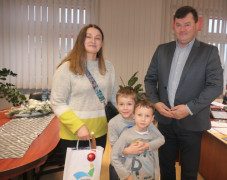Dwaj mali chłopcy, kobieta i mężczyzna stoją obok siebie. Kobieta trzyma w ręku upominkową torbę 