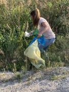 Kobieta biorąca udział w akcji sprzątanie świata - wyposażona jest m.in. w worek koloru żółtego, do którego wrzuca znalezione śmieci