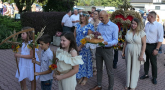 Grupa osób, uczestnicy dożynek. Starostowie dożynek trzymają bochen chleba
