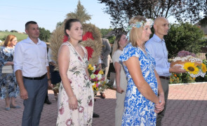Osoby niosą wieniec dożynkowy 