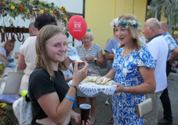 Kobieta częstuje uczestników dożynek chlebem 