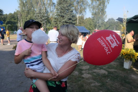 Kobieta trzyma na ręku małego chłopca jedzącego watę cukrową 