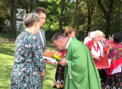 Ksiądz całuje dożynkowy bochen chleba 