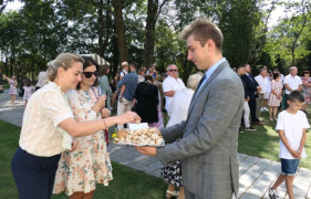 Mężczyzna częstuje kobiety dożynkowym chlebem 