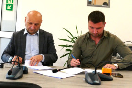 Dwóch panów podczas podpisywania dokumentów 