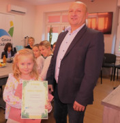 Mężczyzna i dziewczynka stoją obok siebie. Dziewczynka trzyma w ręku dyplom