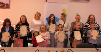 Grupa osób na wspólnym zdjęciu: dorośli i dzieci. Dzieci trzymają w dłoniach dyplomy