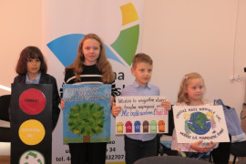 Czwórka dzieci stojąca obok siebie. Dzieci prezentują prace plastyczne 