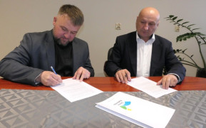 Dwaj panowie siedzą przy stole. Moment podpisania umowy