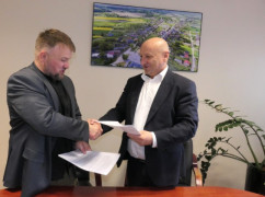 Dwaj panowie podają sobie dłonie i przekazują dokumenty 