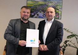 Dwaj panowie stoją obok siebie. Jeden z nich trzyma w dłoniach dokumenty 