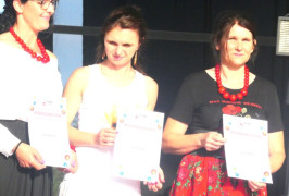 Trzy panie na scenie, pierwsza z lewej Bożena Dobrzańska z KGW "Makowe Panienki" podczas odbierania podziękowań za udział w konkursie kulinarnym "Bitwa Regionów"