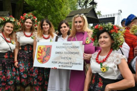 Kobiety w ludowych i codziennych strojach. Widoczna tablica z napisem: Powiat Radomszczański, Gmina Radomsko, Kietlin, KGW "Makowe Panienki" 