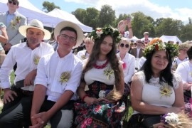 Osoby siedzą obok siebie. Uczestnicy dożynek 
