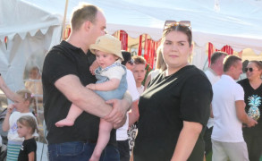 Kobita i mężczyzna stoją obok siebie. Mężczyzna trzyma na ręku małe dziecko 